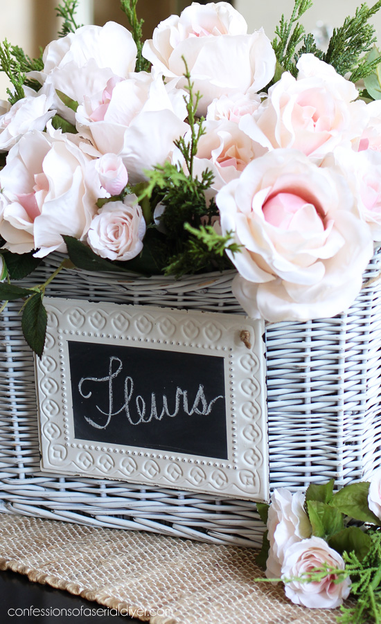 Faux camellias and miniature roses make the perfect Spring centerpiece in this basket. confessionsofaserialdiyer.com