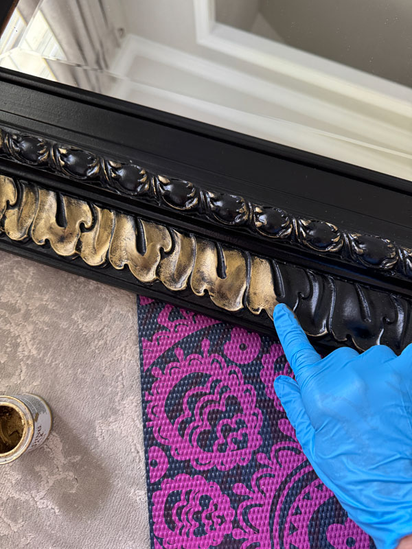 Applying gold gilding wax to the details on a mirror